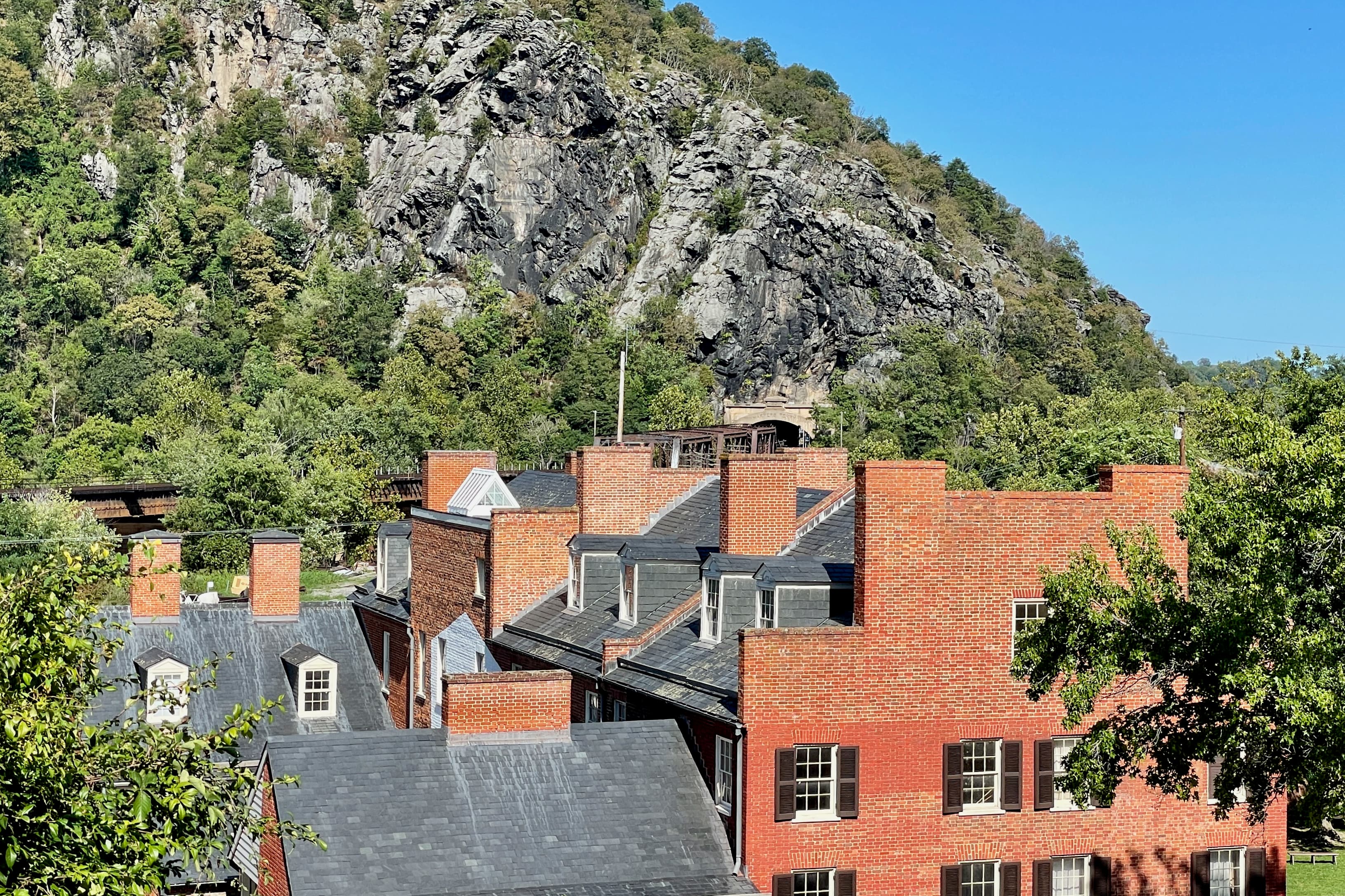 Red brick buildings in Harpers Ferry's Lower Town beneath the rocky Maryland Heights
