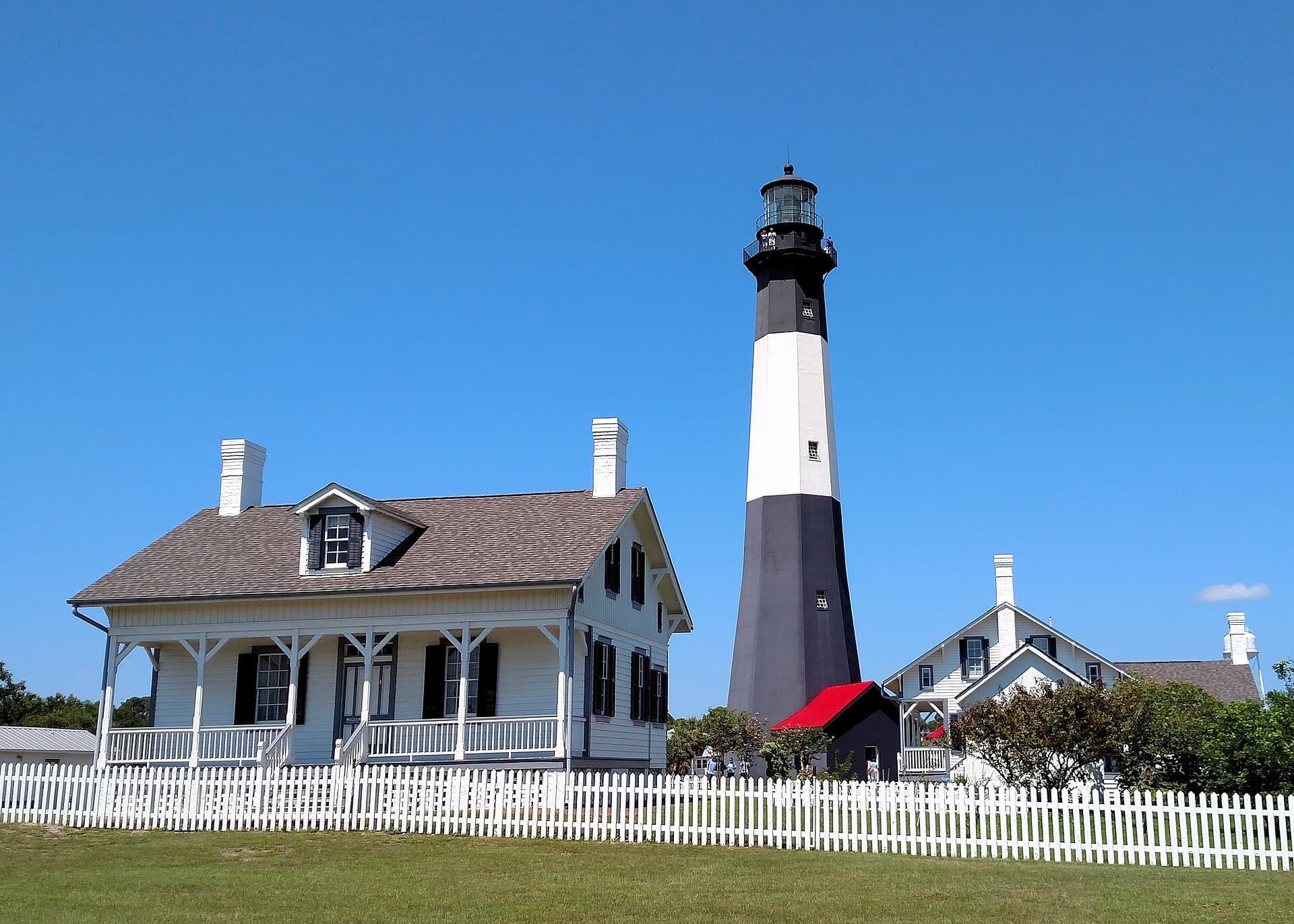 Tybee Island Lighthouse and keeper cottages beneath a clear blue sky